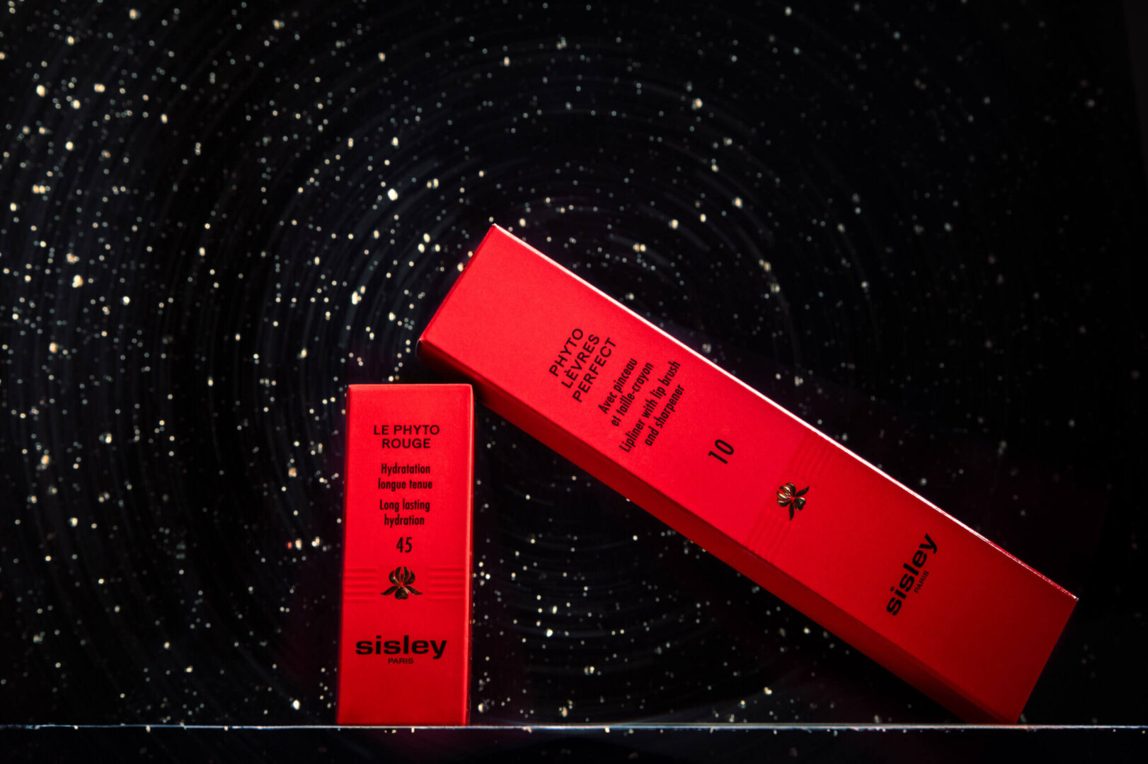 Professionelle Produktfotografie: Luxuriöse rote Verpackungen von Sisley Paris, stilvoll inszeniert auf einem roten Hintergrund – High-End-Aufnahmen für Beauty- und Kosmetikmarken.